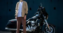 Beste braune Bikerjacken Herren: Ein Mann trägt eine klassische Bikerjacke aus braunem Leder mit Reißverschlüssen und Steppdetails.
