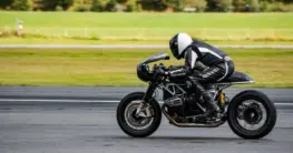 Café Racer braun Lederjacke für Herren mit Stehkragen und Reißverschluss, auf einem Motorrad sitzend