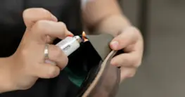 Leder Brennprobe: Eine Flamme testet ein kleines Stück braunes Leder auf Echtheit.
