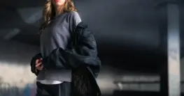 Lederbomberjacke – Schwarze Lederbomberjacke mit gerippten Bündchen und Stehkragen, getragen von einem Mann im urbanen Umfeld.