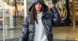 Lederjacke Hoodie Damen Look: Schwarze Bikerjacke über grauem Kapuzenpullover für lässigen Streetstyle.