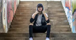 Lederjacke Hoodie Herren: Schwarze Bikerjacke über grauem Hoodie für einen lässigen Streetwear-Look.