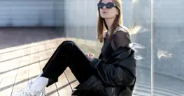 Lederjacke Sneaker Damen in schwarzem Biker-Schnitt, kombiniert mit weißen Sneakern und Jeans für einen lässigen Look.