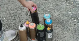 Imprägnierspray Inhaltsstoffe: Mann sprüht Lederjacke im Freien, achtet auf sichere Anwendung und Belüftung.
